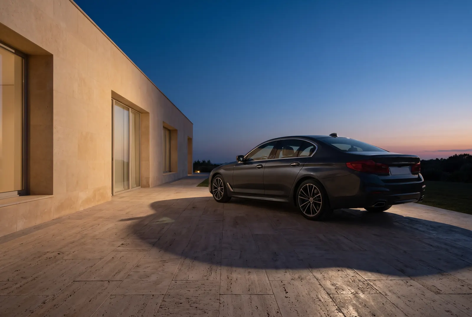 Un sedán elegante estacionado junto a una casa de piedra caliza al atardecer